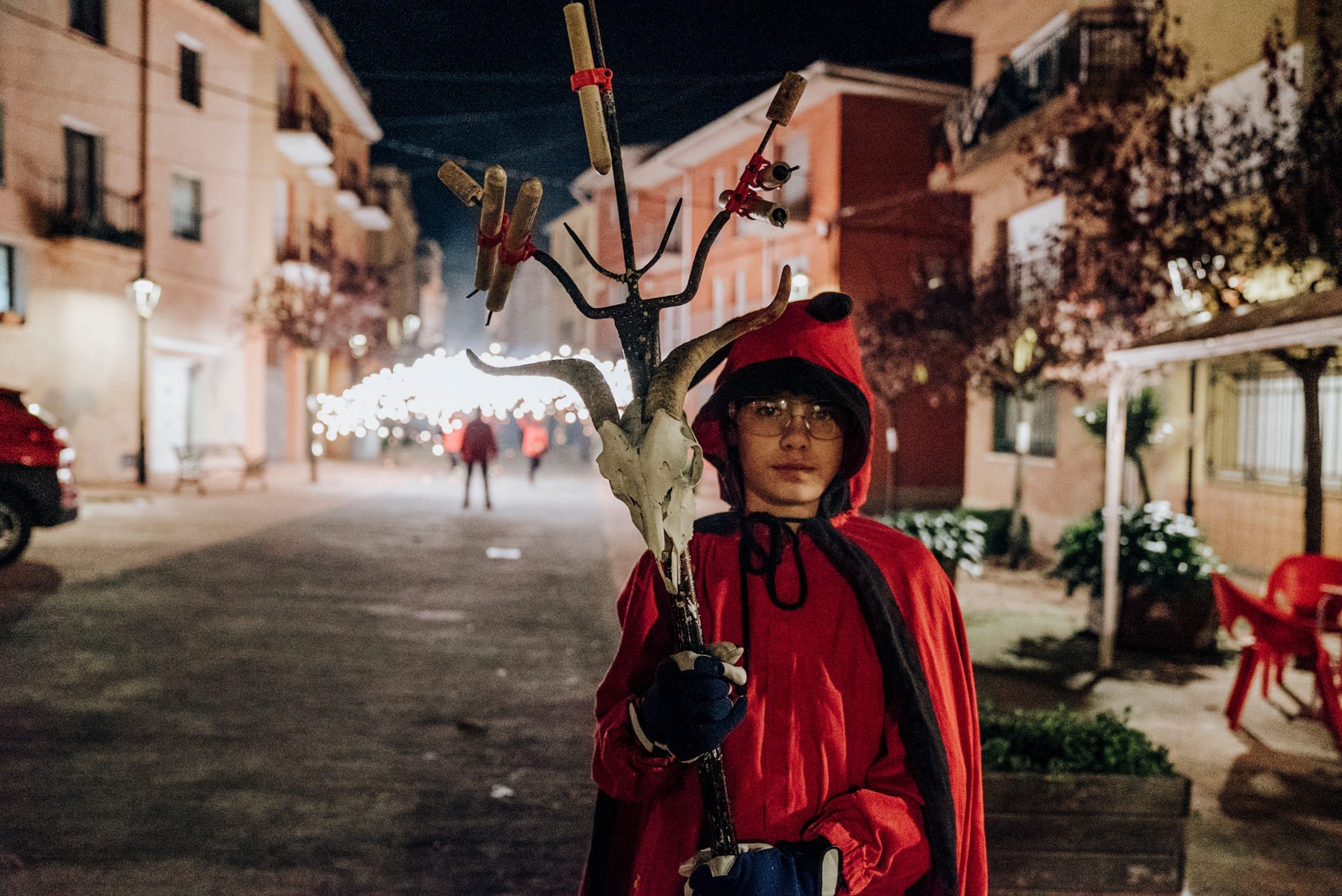 Un jove diable sosté el ceptrot amb el crani de boc, de nit al mig del carrer